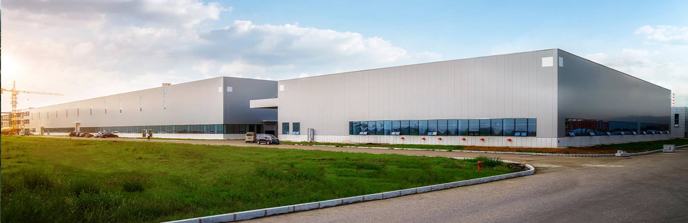 Image of two connected grey warehouse buildings on a piece of rural land.