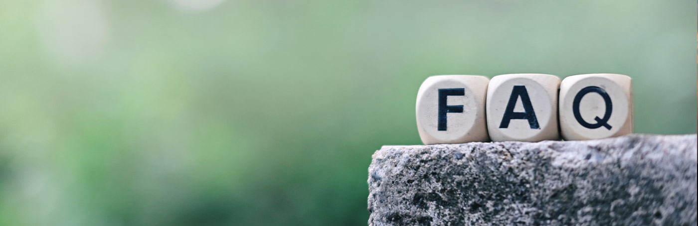 Wooden dice with the letters FAQ sitting on top of a granite rock