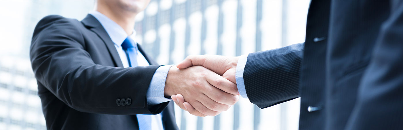 Close-up image of two business men in business suits shaking hands