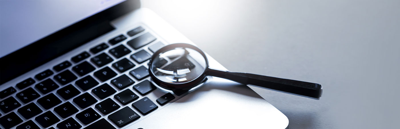 Laptop with a magnifying glass resting on top of the keyboard