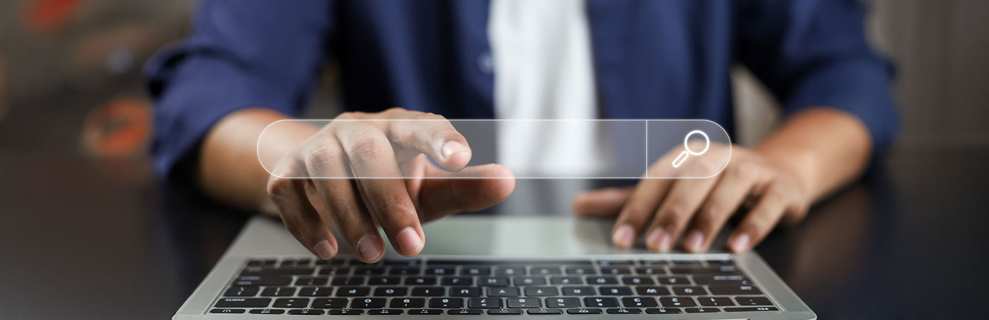 A man facing the camera, pointing at a search bar graphic overlay on the screen