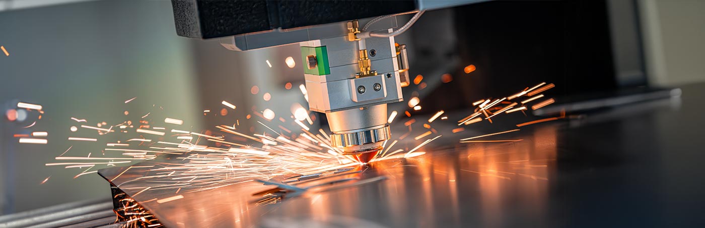 A close-up image of a manufacturing tool striking metal, with sparks flying