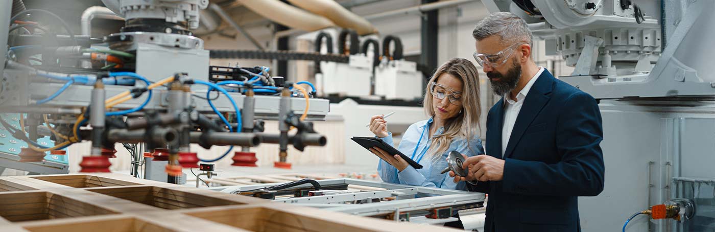 A man and a woman looking over information on the clipboard in a manufacturing warehouse