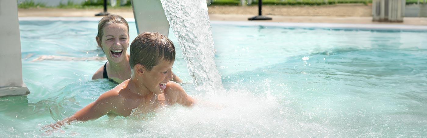 A woman and her son swimming in a pool on a sunny day